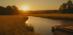 the sun is setting over the water in the field