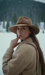 a woman wearing a brown hat stands in the snow