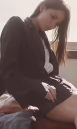 a girl sitting and holding a purse is posing for the camera