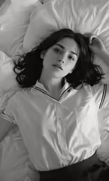 black and white photograph of young woman lying on bed