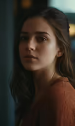 a woman in brown is standing in front of a window