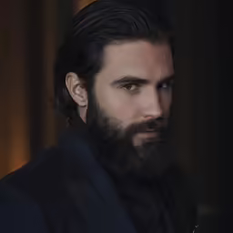 a man in a black suit stares straight ahead