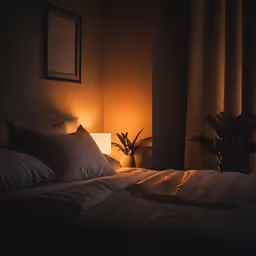 a bed with two pillows and a lamp at night