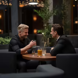 two men at a table sharing drinks and talking