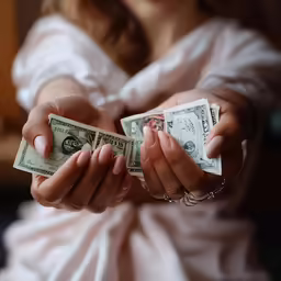 two women are holding a bunch of dollar bills