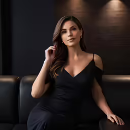 a beautiful woman posing on top of a black couch