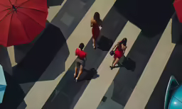 three people wearing red walking along a black and white striped street
