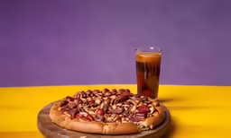 a pizza on a table next to a drink