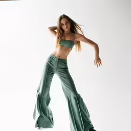 woman posing with her arms behind her head with one foot raised in the air
