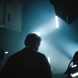 a person looking to the left and a spotlight shining through the darkness