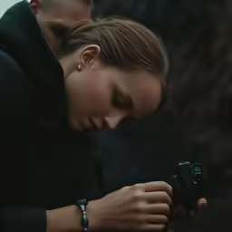 woman holding and observing camera in close proximity