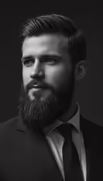 man in black suit with a beard, staring at the camera