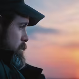 the man is looking through a window with the sun in the background