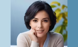 a beautiful woman in white shirt leaning on a blue wall