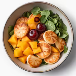 a bowl of food with spinach, cherries and peaches