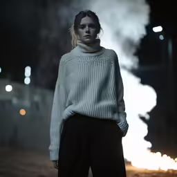 a woman standing in front of some dark lights