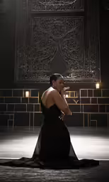 a woman is sitting down in front of a wall