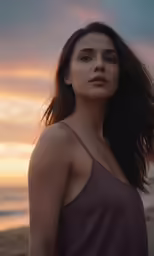 woman standing in front of water during sunset