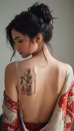 a woman with a back tattoo has writing in japanese characters