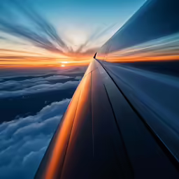 an airplane wing and clouds at sunset from the window