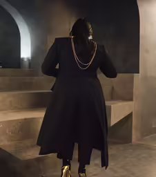 a woman in a black dress standing on stairs