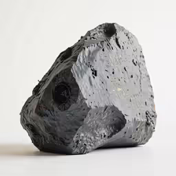 a black and white rock is sitting against a white wall