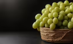 grapes are arranged in a large bowl on a black table