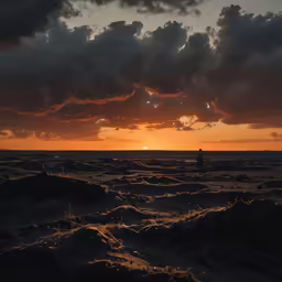 the silhouette of people walking down a beach at sunset
