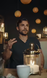 a man is sitting at a table with food and a lantern