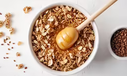 a bowl of cereal and a cup of oats on a white surface