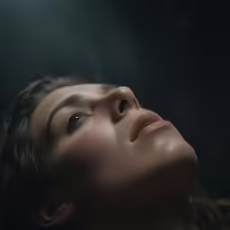an image of a woman in the dark looking up