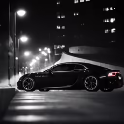 a black car parked on a sidewalk with headlights in the background