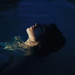 a young woman is swimming in the water,a girl swims in the water in a dark pool