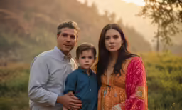 a family poses in a field with the sun setting behind them