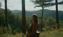 a person standing outside, with mountains in the background