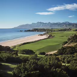 an empty golf course is shown with water, hills, and trees