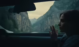 a girl waving from the back of a car