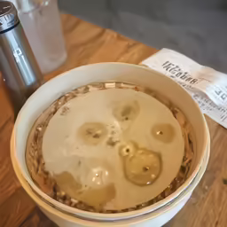 a brown drink sits in a bowl and beside a water bottle
