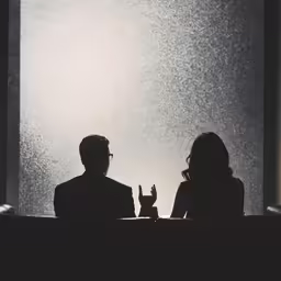 a couple seated down and looking out from their windows