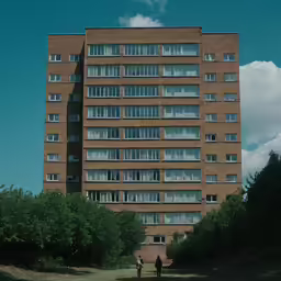 people walk through a park next to a building