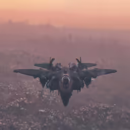 two airplanes are flying in the air over a grassy field