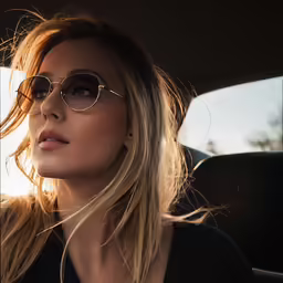 a woman wearing glasses sitting in a car