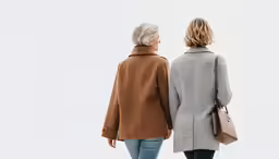 two women wearing coats, each one in brown and the other in gray