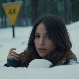 a woman with brown hair is laying in the snow