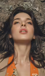 a beautiful woman in an orange top sitting on the ground