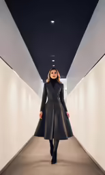 woman in black coat walking down a hallway