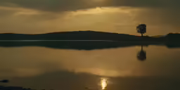 the setting sun reflects in the still waters of a lake
