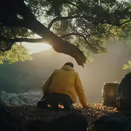 man standing under tree on rocky ground in forest