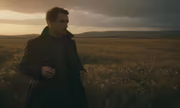 the man is standing in a field staring at something