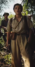 woman wearing large brown shirt and cap walking through the jungle